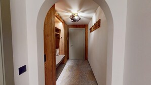 Ein Flur mit Holztür, einer Deckenleuchte und einem an der Wand befestigten Kleiderhaken.