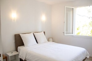 Ein Schlafzimmer mit einem Bett, Nachttischen, einem Fenster und Wandleuchten.