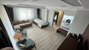 Ένα σύγχρονο δωμάτιο ξενοδοχείου με έναν καναπέ, ένα κρεβάτι, ένα μικρό τραπέζι και ένα γραφείο.
