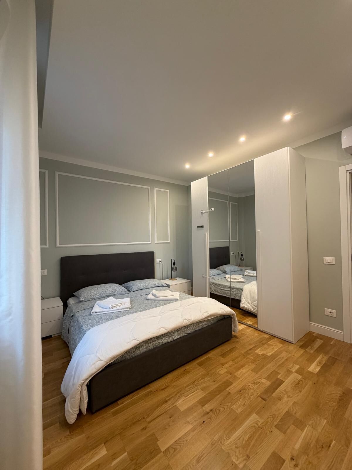 Un dormitorio con una cama grande, una mesita de noche, un espejo y un armario.