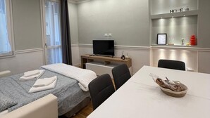 Een moderne hotelkamer met een bed, een bureau, een televisie en een kleine kitchenette.