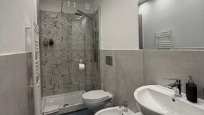 Een moderne badkamer met douche, toilet, bidet en een groot wastafel.