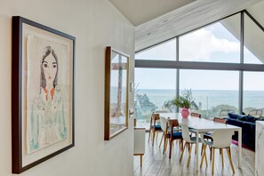 Un comedor moderno con una mesa grande, sillas y vista al mar.
