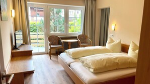 Habitación de hotel con cama, escritorio, silla, mesa y vistas al exterior.