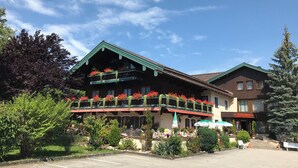 Un hotel con un balcón decorado con flores, un restaurante llamado 'Zellerhof' y un aparcamiento.