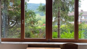 Una habitación con un ventanal que ofrece vistas a un área boscosa y una casa al fondo.
