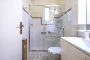 A bathroom with a glass-enclosed shower, a toilet, and a sink. - Urban apartment 5' minutes from Acropolis (Athina)