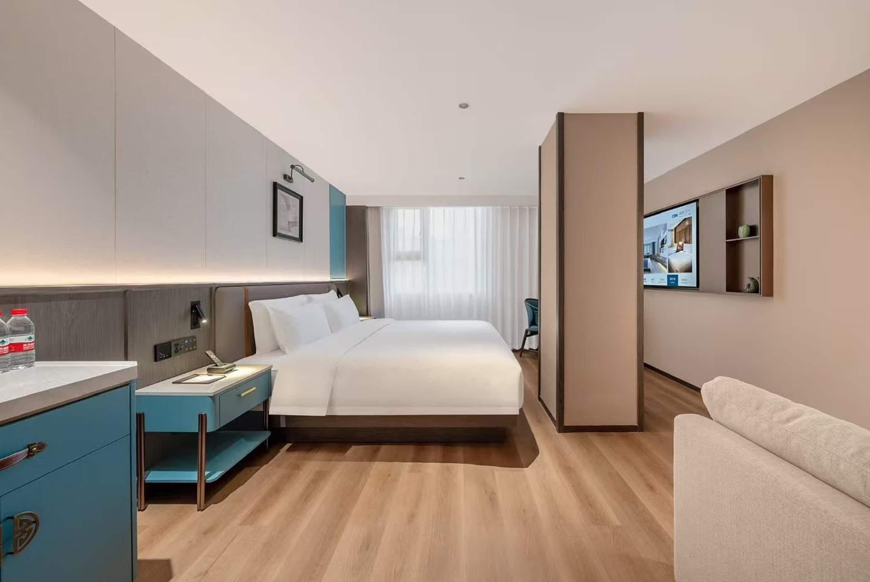 Habitación de hotel con cama, escritorio, silla, televisor y baño.