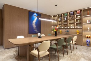 Uma sala de jantar moderna com uma longa mesa de madeira, seis cadeiras e uma figura decorativa de panda.