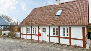 Un bâtiment traditionnel avec un toit en tuiles, des murs blancs rehaussés de bordures marron et une petite fenêtre.
