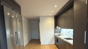 A modern kitchen with wooden flooring, built-in appliances, and dark cabinetry. - Stylish luxury suite with magical golf views near the city (Örebro)