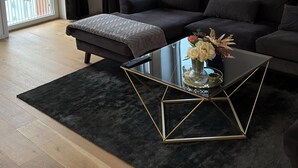A modern living room with a sofa, a glass coffee table, and a view of a balcony. - Stylish luxury suite with magical golf views near the city (Örebro)
