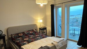 A bedroom with a bed, a nightstand, a lamp, a window with a view, and a ceiling fan. - Stylish luxury suite with magical golf views near the city (Örebro)