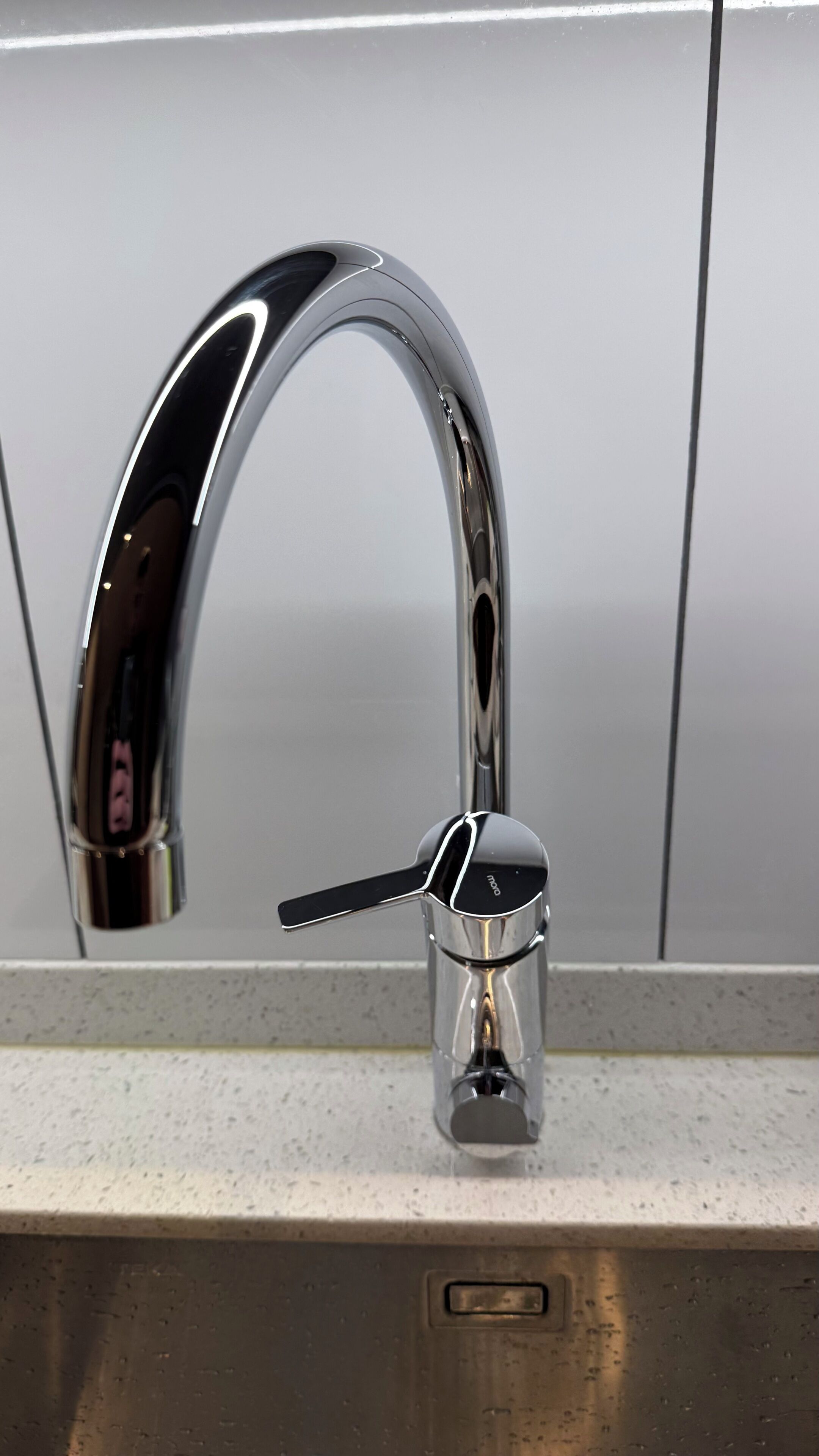 Un robinet chromé avec une manette en forme de levier, installé sur un plan de travail de cuisine.
