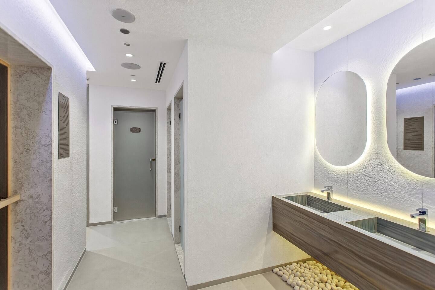 A modern bathroom with a double sink, a large mirror, and a lighted wall feature.