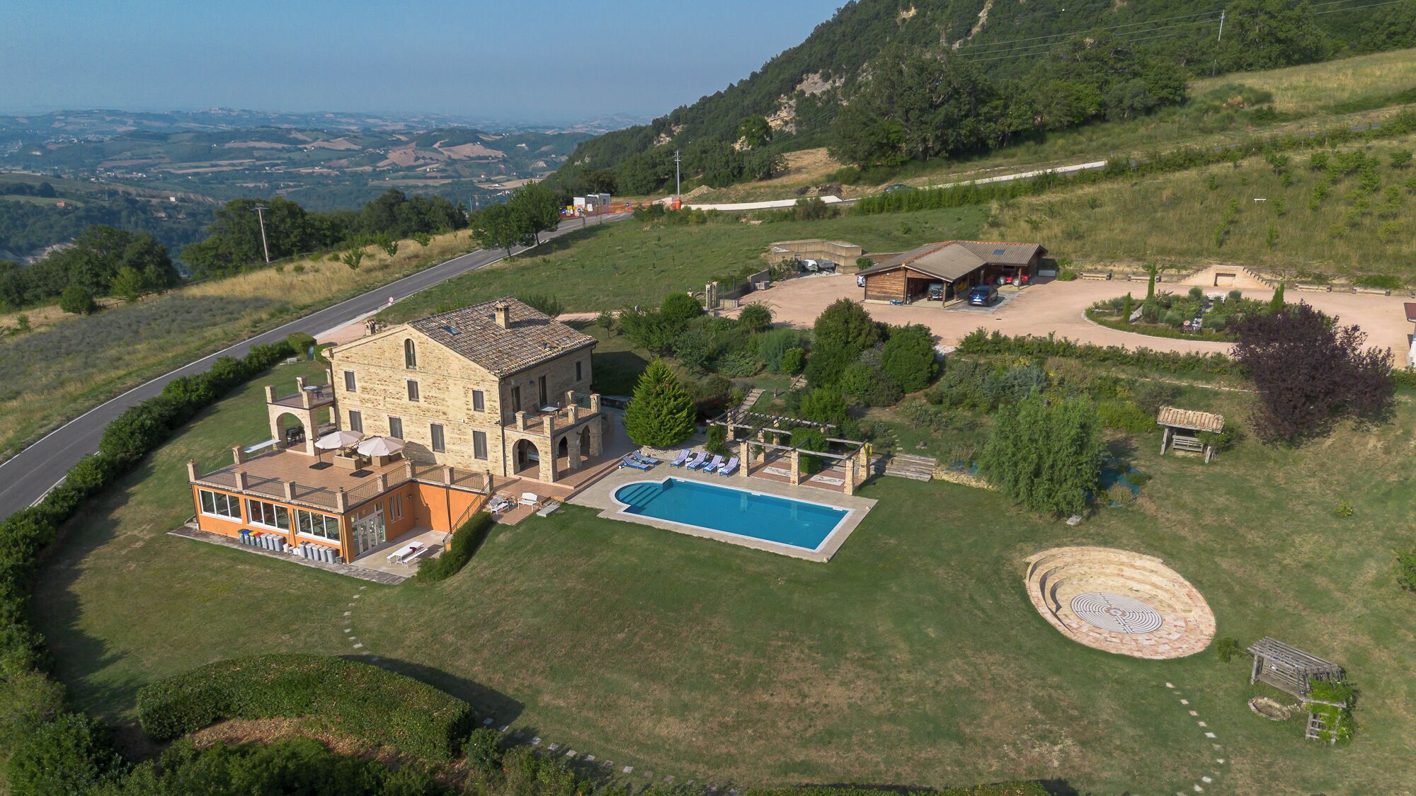 A large property with a swimming pool, outdoor seating, and a view of the surrounding landscape.