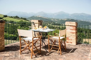 Ein Tisch mit Stühlen auf einer Terrasse mit Blick auf die Berge.
