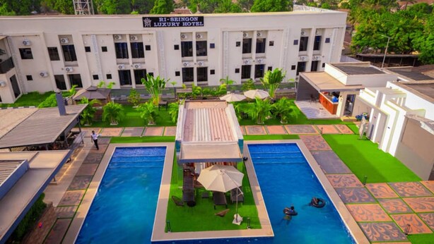 A rooftop pool area with two pools, surrounded by a garden and a building labeled 'RI-SEINGON LUXURY HOTEL'.