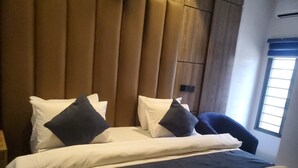 A hotel room with a bed, pillows, a chair, and a window.