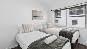 Ett hotellrum med två sängar, en takfläkt, ett fönster med utsikt och en tavla på väggen.
