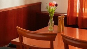 A corner of a room with a wooden table, a vase with flowers, and a window with curtains. - Gästehaus Freitag  (Sankt Georgen im Lavanttal)
