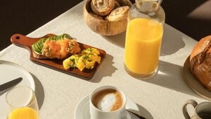 A breakfast setting with croissants, scrambled eggs, and a glass of orange juice. - Gästehaus Freitag  (Sankt Georgen im Lavanttal)