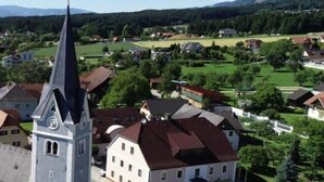 A town with a prominent church tower, a central building with a red roof, and surrounding residential houses. - Gästehaus Freitag  (Sankt Georgen im Lavanttal)