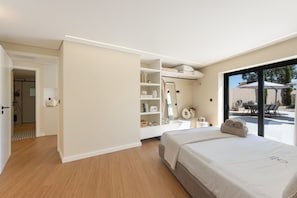 Un dormitorio moderno con una cama grande, un vestidor y vistas a un patio exterior.