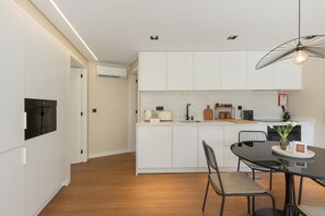 Una cocina moderna con armarios blancos, una isla central y un comedor con mesa y sillas.