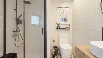 Une salle de bain moderne avec une douche à parois de verre, des toilettes et un espace lavabo.