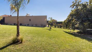 A grassy area with a building, trees, and a clear sky.