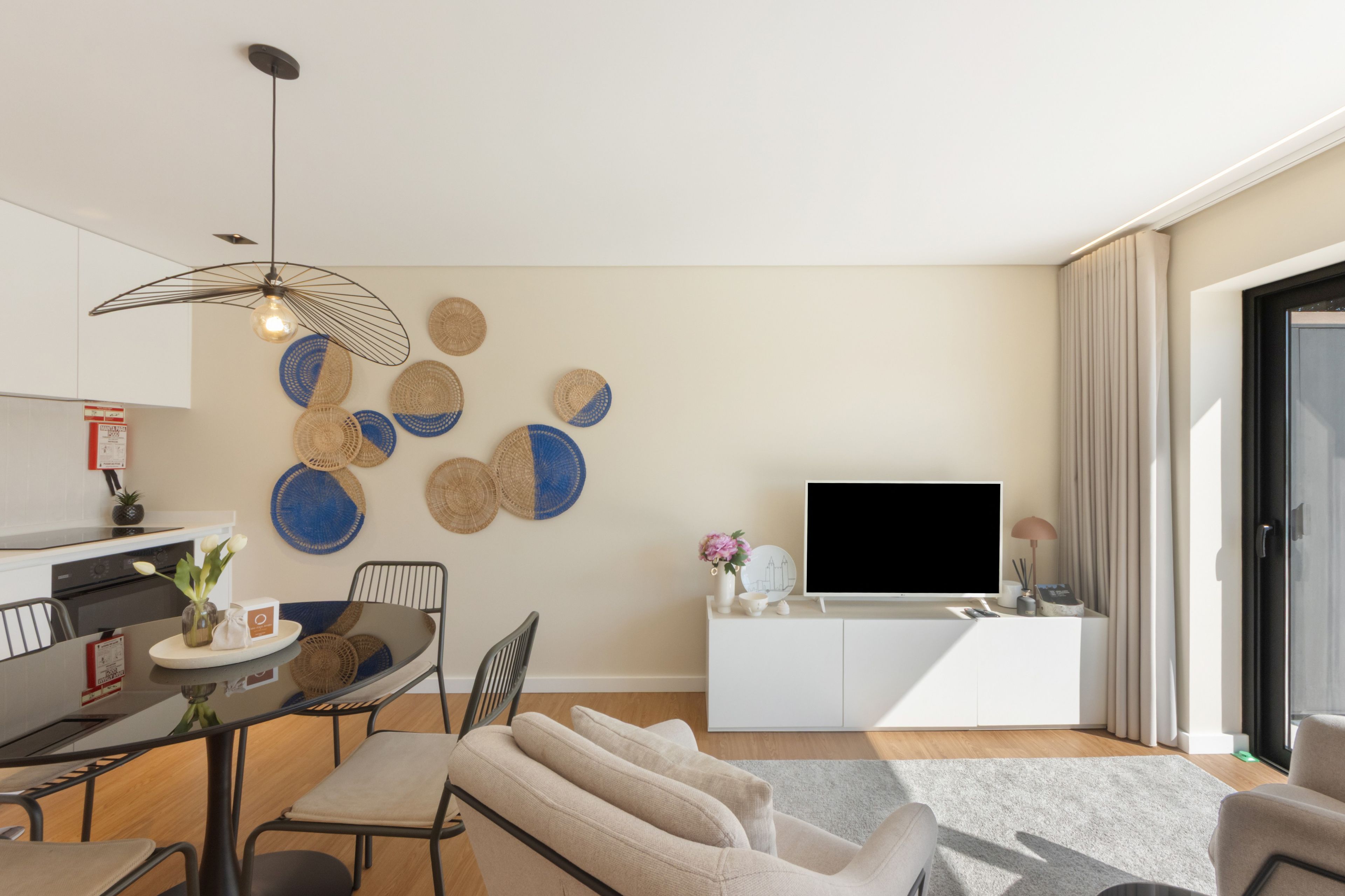 Un salon moderne avec un coin repas, un téléviseur à écran plat et une cuisine en arrière-plan.