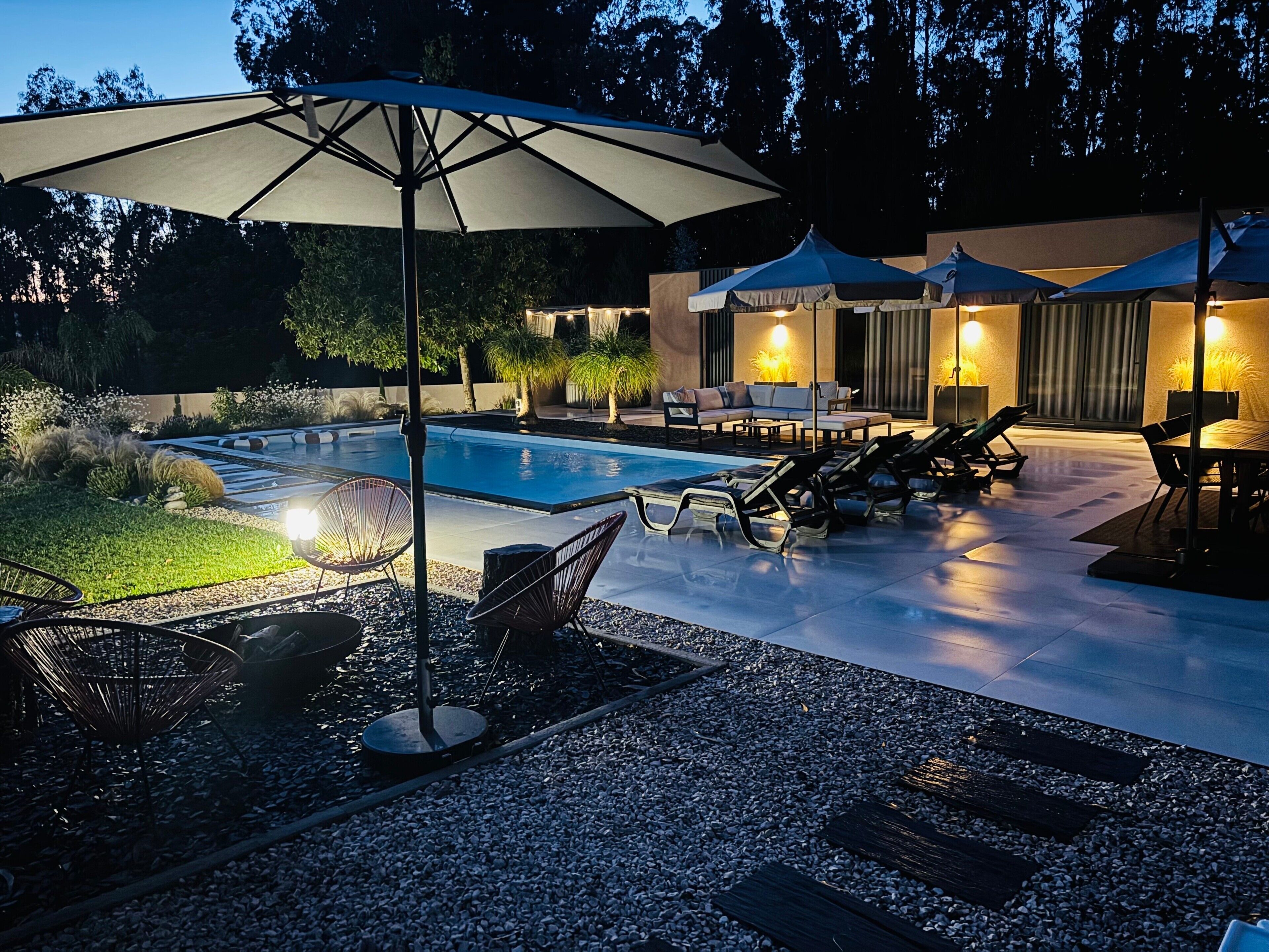 A swimming pool with lounge chairs and umbrellas, surrounded by a patio area with seating.