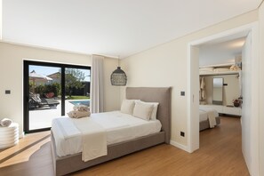 Un dormitorio con cama, ventana grande y vista a una piscina.