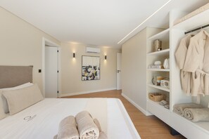 A modern bedroom with a large bed, a wardrobe, and a wall-mounted air conditioner.