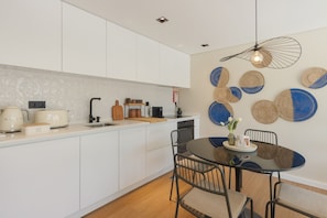 A modern kitchen with white cabinets, a round dining table with chairs, and decorative wall hangings.
