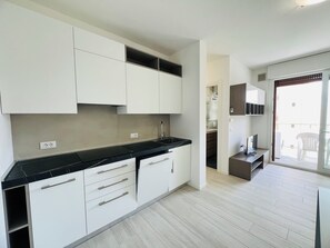 Eine moderne Küche mit weißen Schränken, schwarzen Arbeitsplatten und Holzboden.