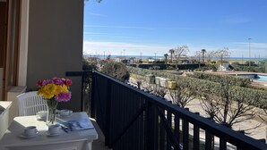 A balcony with a table, chairs, and a vase of flowers. - Sea view apartment in central Bibione (Bibione)
