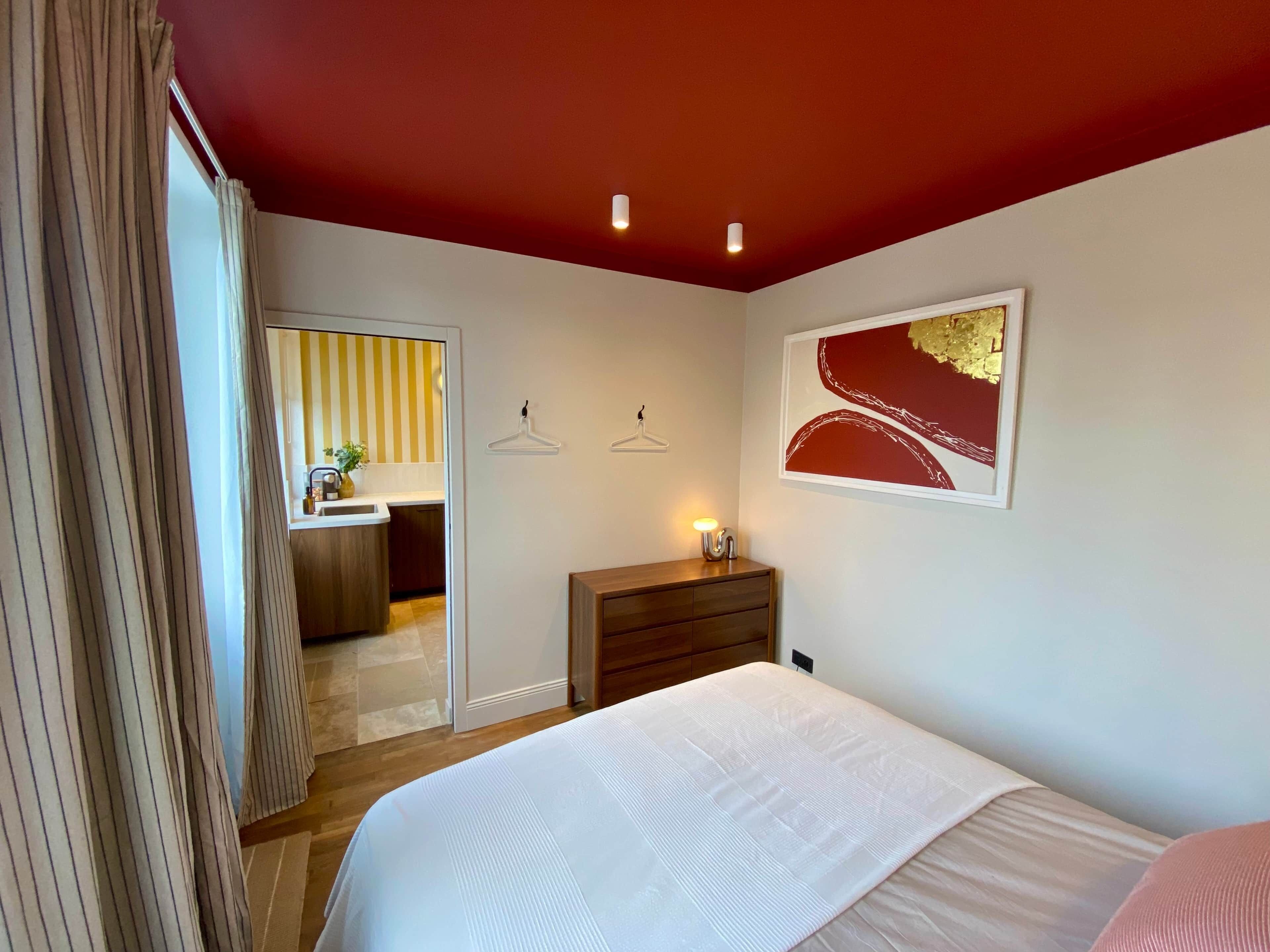 A bedroom with a bed, a dresser, a mirror, and a door leading to a bathroom.