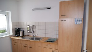 Une cuisine avec des meubles de rangement en bois, un évier en acier inoxydable, une machine à café et une fenêtre.