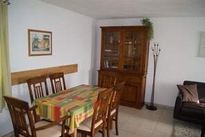 Een eetgedeelte met een houten tafel, stoelen, een kast en een bank.