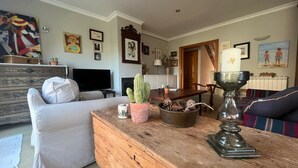 A living room with a sofa, a wooden coffee table, a cactus, and a TV. - Holiday home with private pool, Sant Pere Pescador (Sant Pere Pescador)