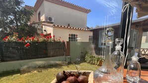 A patio with a wooden table, a glass decanter, and a bottle, a potted plant, and a metal container with fruits. - Holiday home with private pool, Sant Pere Pescador (Sant Pere Pescador)