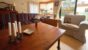 A living room with a wooden coffee table, striped sofa, and a beige armchair. - Holiday home with private pool, Sant Pere Pescador (Sant Pere Pescador)