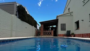 A swimming pool with a clear blue sky, a white building with a covered patio, and a brick structure. - Holiday home with private pool, Sant Pere Pescador (Sant Pere Pescador)