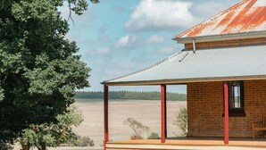 A rustic building with a corrugated metal roof, a brick exterior, and a covered porch.