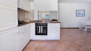 Una cocina con armarios blancos, estufa y ventana.