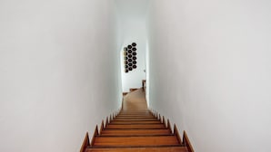 Una escalera con escalones de madera y paredes blancas.