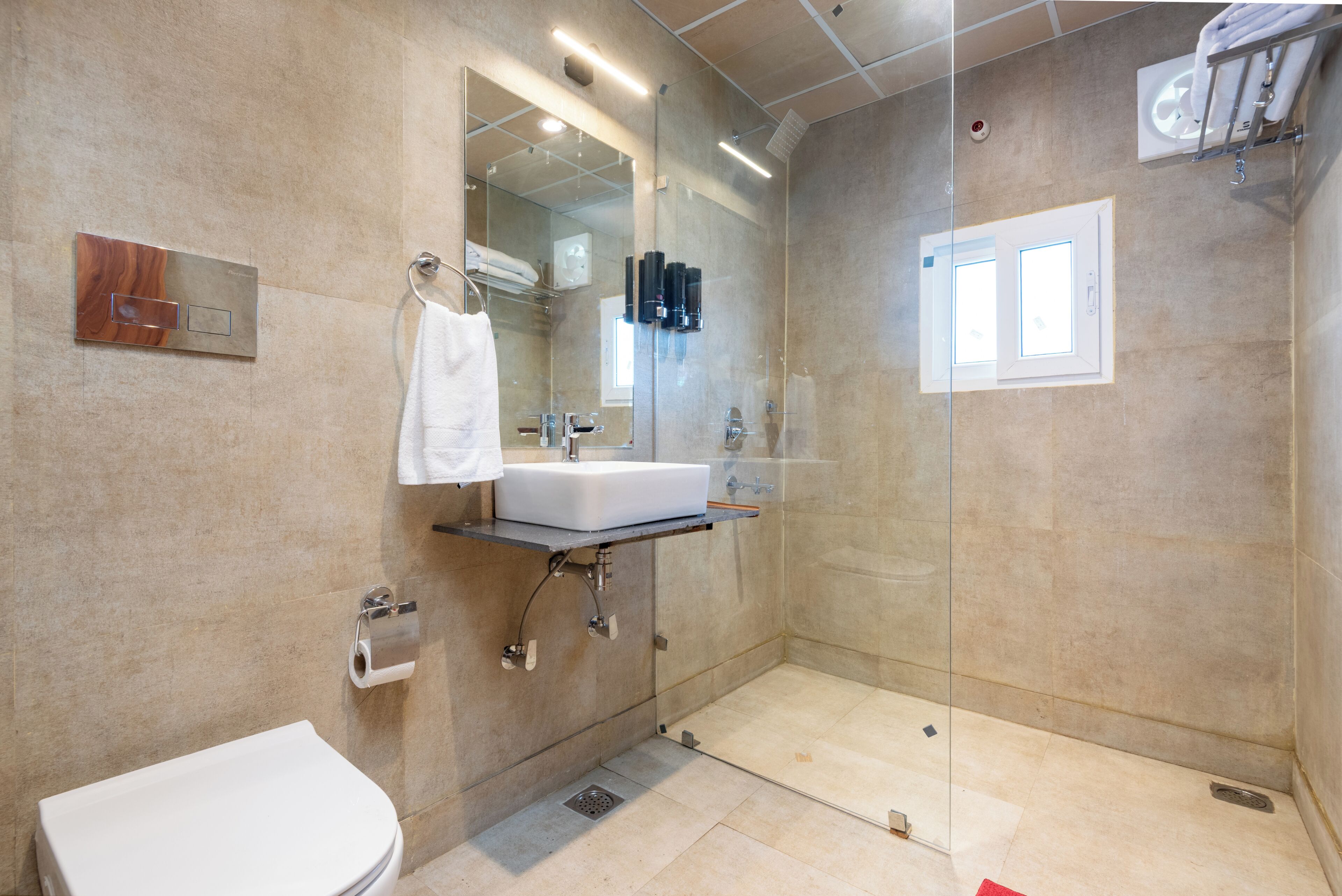 Un baño moderno con cabina de ducha de vidrio, un lavabo blanco y un inodoro.
