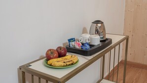 A breakfast tray with apples, bananas, coffee cups, and a kettle on a table.